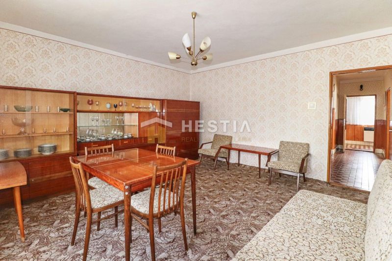 Interiér rodinného domu s nábytkem z 20. století a vzorovaným kobercem.