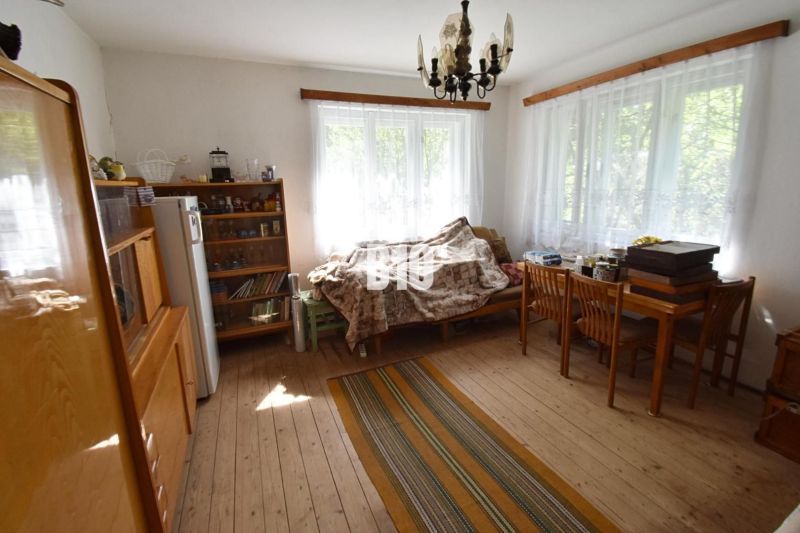 Obývací pokoj v rodinném domě s podlahou s dřevěným dekorem, sedačkou a stolem.