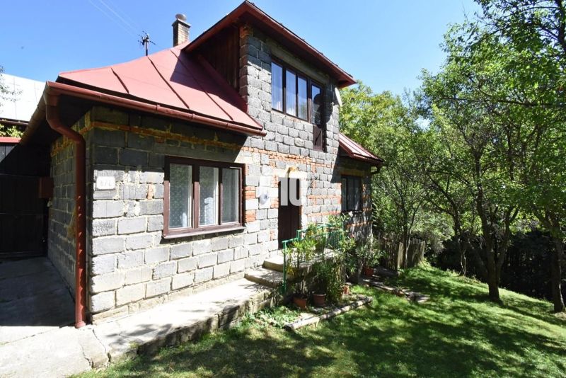 Rodinný dům v Dlhom Poli obklopený zelení s podkrovím a červenou střechou.