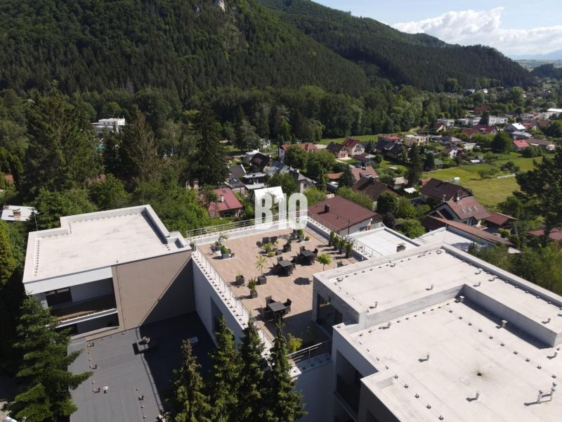 Pohled na střešní terasu mezi budovami obklopenými přírodou v Rajeckých Teplicích na ulici M. R. Štefánika.