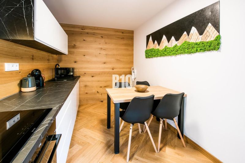 Interiér rekreačního apartmánu s kuchyní, jídelním stolem a podlahou s dřevěným dekorem.
