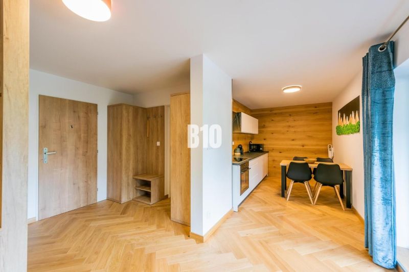 Kuchyně a jídelní prostor v rekreačním apartmánu s podlahou s dřevěným dekorem.