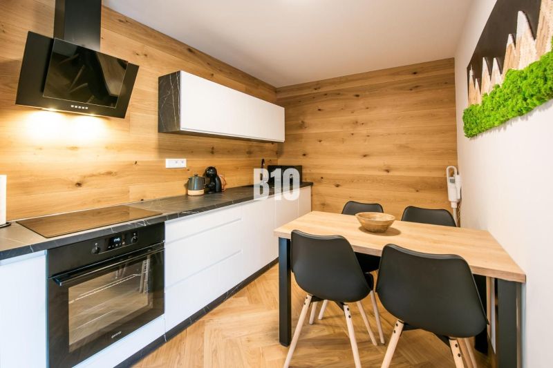 Kuchyně v rekreačním apartmánu s podlahou s dřevěným dekorem a stylovým nábytkem.