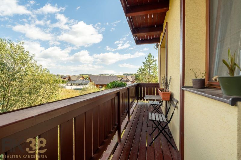 Balkon 2-pokojového bytu s dřevěným obložením ve Velké Lomnici, výhled na okolní krajinu.