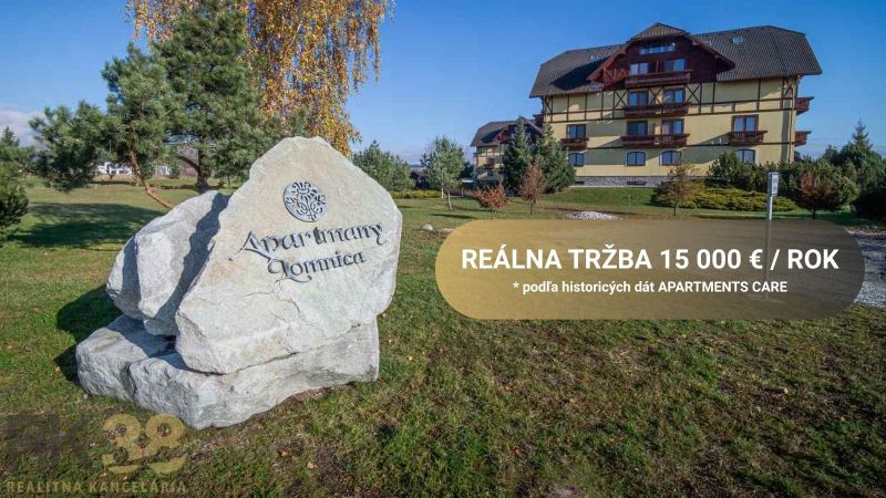 Velká Lomnica: Apartmány, zeleň, budovy v pozadí, nápis na skále.