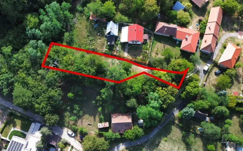 Letecký pohled na parcelu v zahradách Kolačna, obklopenou zelení a nemovitostmi.