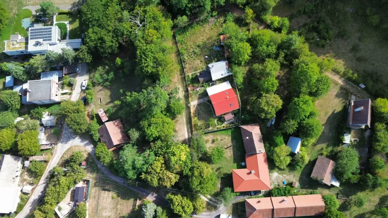 Letecký pohled na zahrady a domy v Kolačne, obklopené hustou zelení.