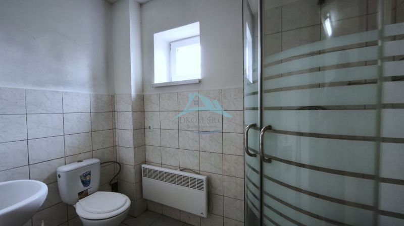 Koupelna s toaletou a sprchovým koutem ve výrobních prostorách.