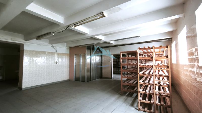Výrobní prostory s dlaždicovou podlahou, dřevěnými regály a výtahem.
