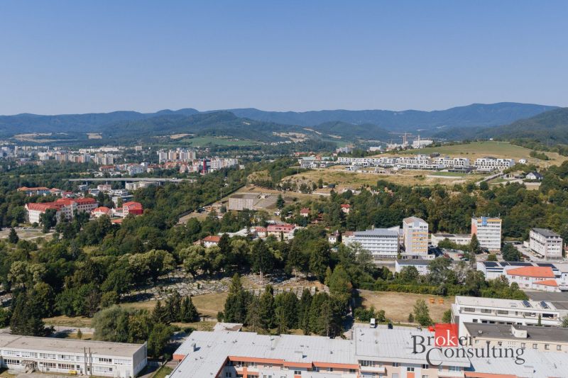 Pohled na panorama Banské Bystrice z Komenského, vidět rodinné domy a přírodu.