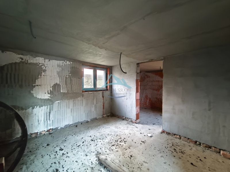 Stavební interiér rodinného domu s nedokončenou omítkou a betonovou podlahou.