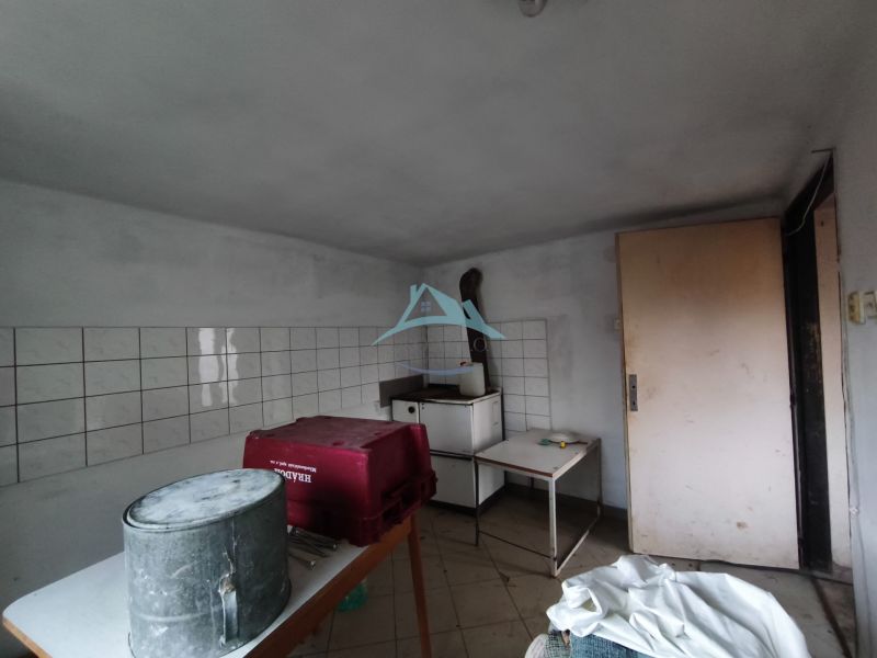 Pokoj v rodinném domě se stolem, kbelíkem a obklady na stěně.
