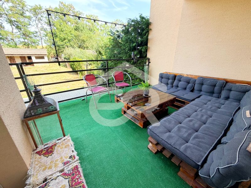 Balkon rodinného domu s paletovým posezením, zeleným kobercem a výhledem na zahradu.
