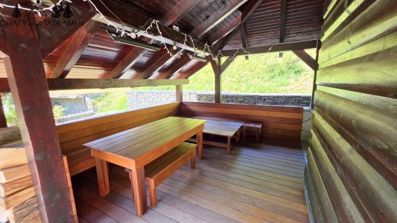 Exteriér chaty v Jarabej s dřevěným přístřeškem a posezením.