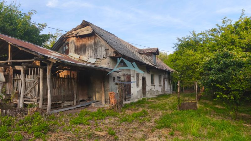 Starší rodinný dům v obci Čelovce, obklopený zelení a dřevěnými přístavbami.