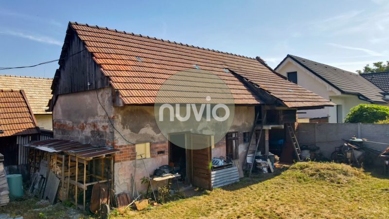 Rodinný dům v Žabokrekách s neudržovanou zahradou a hospodářskou budovou na pozemku.