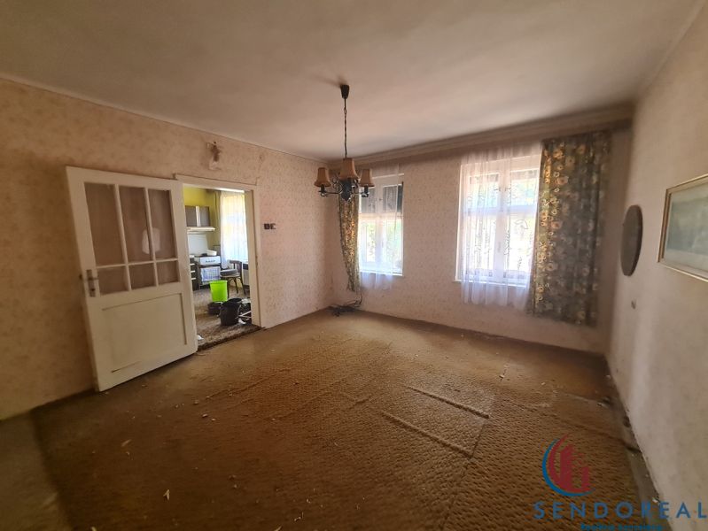 Obývací pokoj v rodinném domě s kobercovou podlahou a starožitným lustrem.