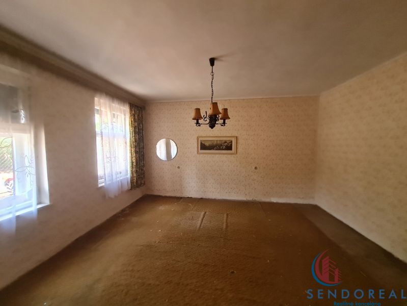Interiér rodinného domu s kobercovou podlahou, světlem a záclonami na oknech.