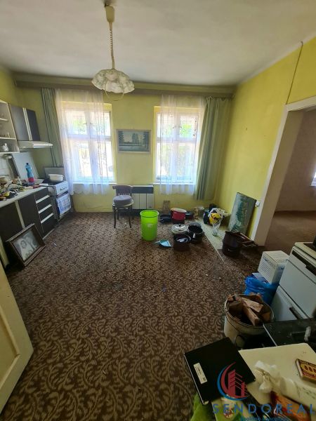 Obývací pokoj s kobercovým dekorem, nábytek a plastové kbelíky v rodinném domě.