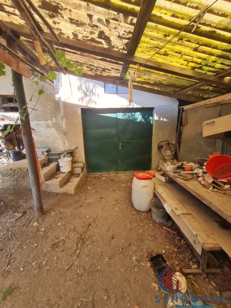 Garáž u rodinného domu v Dolních Otrokovicích s plechovými vraty a přístřeškem.