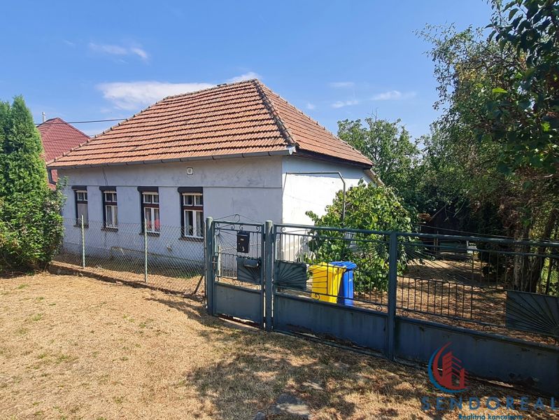 Rodinný dům v Dolních Otrokovicích s plotem a zahradou na slunném pozemku.