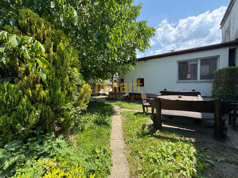 Zahrada rodinného domu v Bratislavě - Ružinově na Sennej ulici s dřevěným posezením.