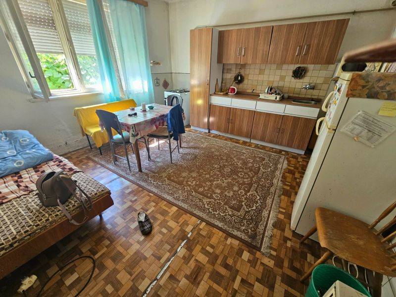 Kuchyně v rodinném domě s jídelním stolem, kuchyňskou linkou a podlahou s dřevěným dekorem.