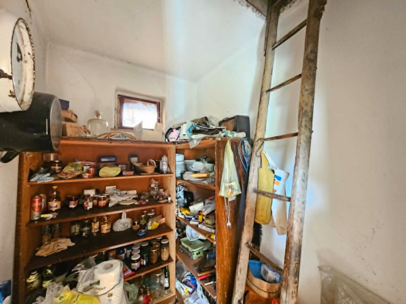 Police s potravinami a žebřík v místnosti rodinného domu.