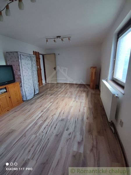 Pokoj v rodinném domě s televizí a podlahou s dřevěným dekorem.