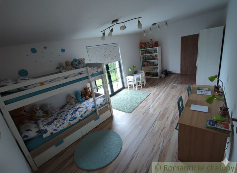 Dětský pokoj s patrovou postelí, psacím stolem a podlahou s dřevěným dekorem.
