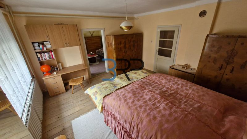 Ložnice v rodinném domě s dřevěným dekorem a starožitným nábytkem.