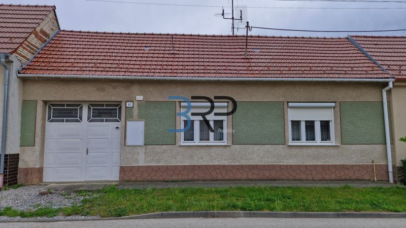 Rodinný dům v Mokrém Háji s červenou střechou a garážovými dveřmi.