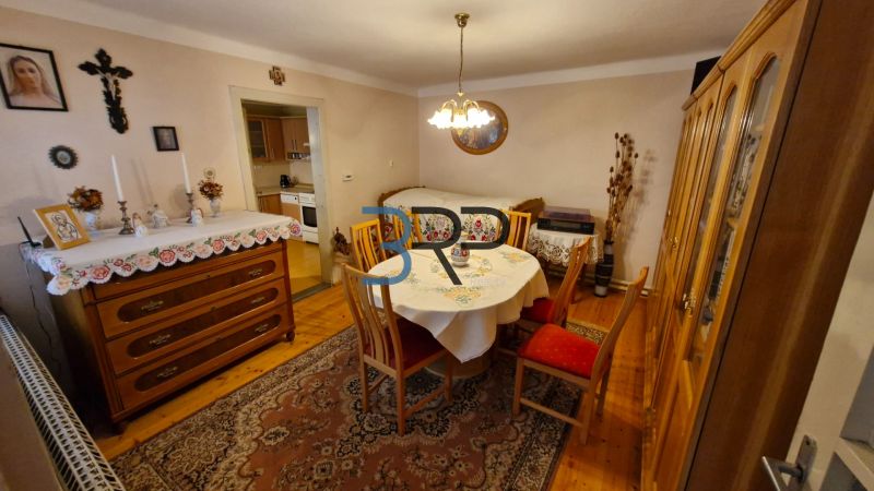 Jídelna v rodinném domě s dřevěným dekorem, stolem a komodou.