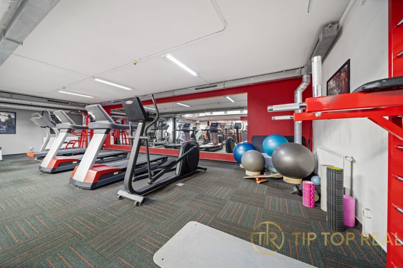 Fitness centrum s běžeckými pásy a cvičebními pomůckami v obchodních prostorách.