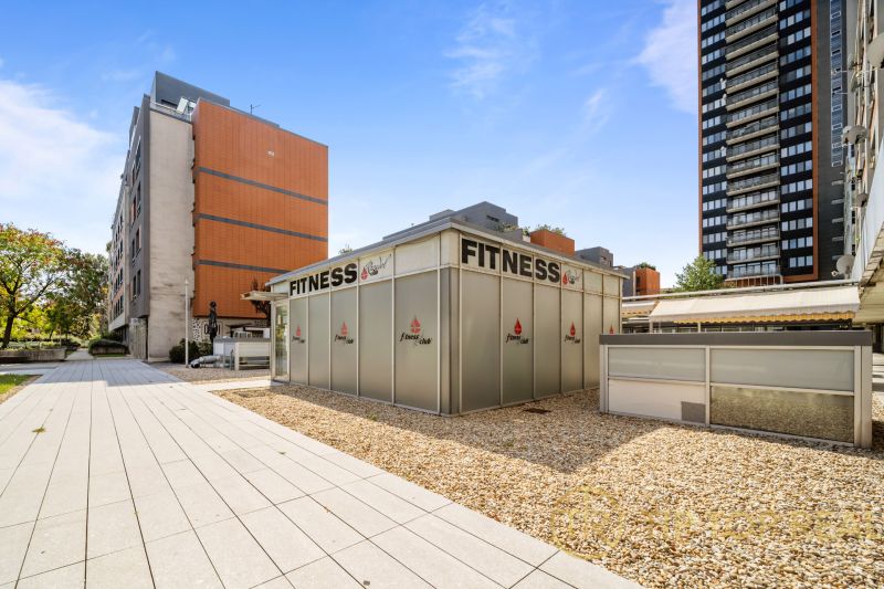 Exteriér Bratislava - Nivy, Trenčianska: Fitness centrum obklopené moderními budovami a zpevněnými plochami.