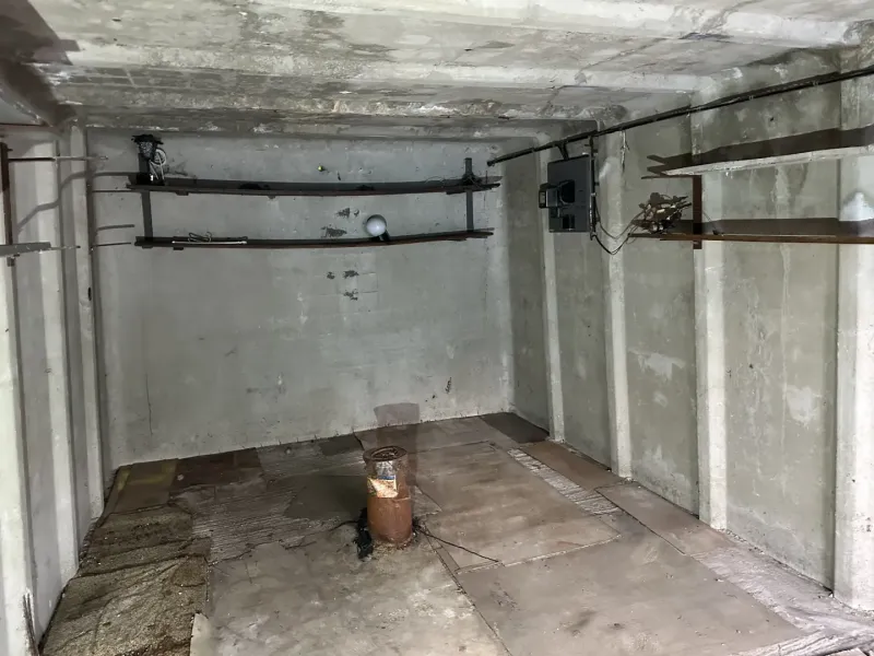 Betonová místnost s držáky na stěně a podlahou s dřevěným dekorem v garážích.