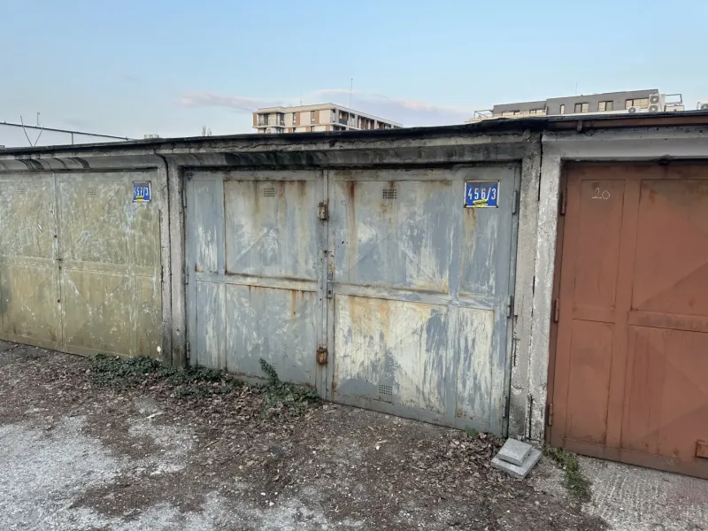 Opuštěné garáže v Bratislavě - Novém Městě s opadanou omítkou a plechovými dveřmi.