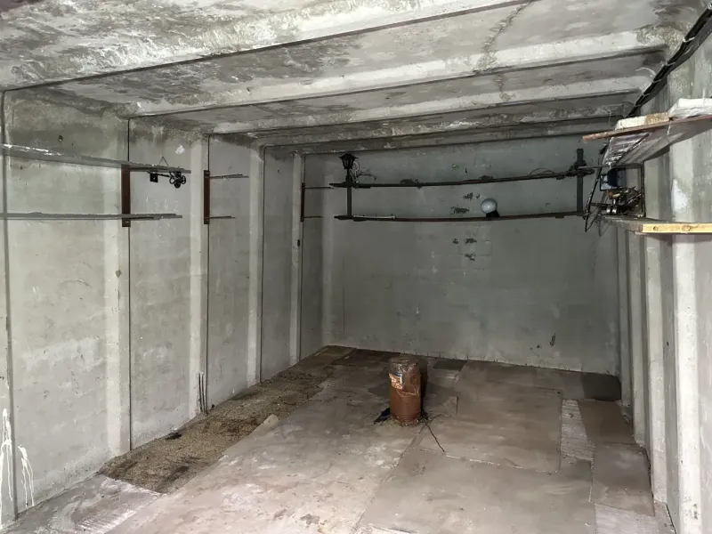 Prázdná betonová místnost s trubkami a osvětlením, interiér garáže.