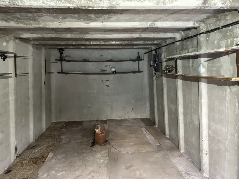 Prázdný betonový interiér garáží s policemi a osvětlením.