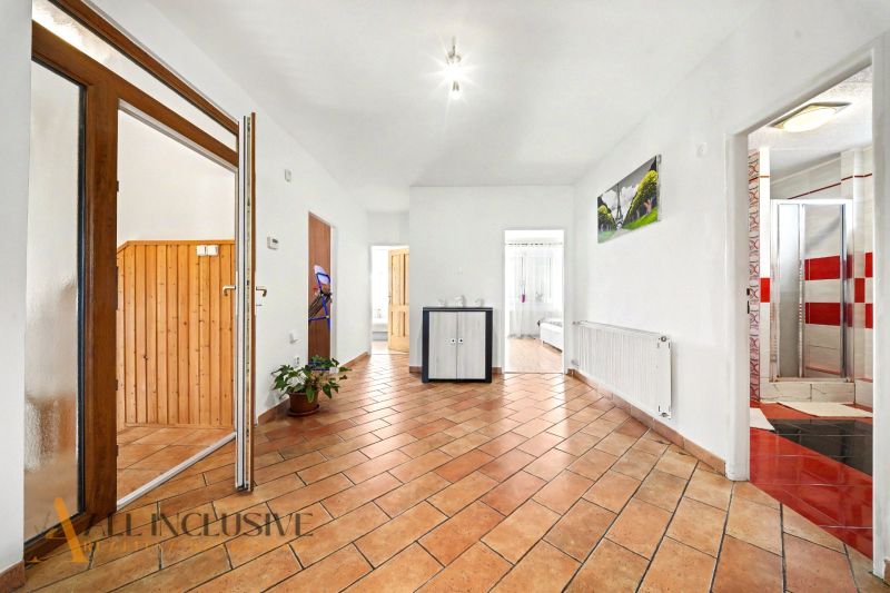 Prostorná chodba s dlaždicovou podlahou v rodinném domě, s dřevěnými prvky interiéru.