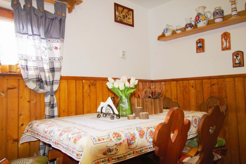 Interiér chaty se stolem, rustikální dekorací a dřevěným obložením stěn.