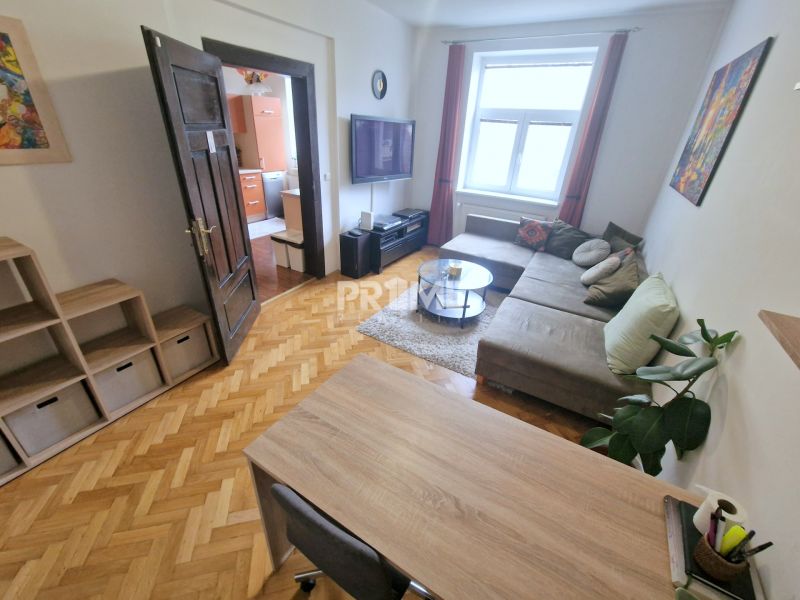 Obývací pokoj ve 3-pokojovém bytě disponuje pohodlnou sedací soupravou a podlahou s dřevěným dekorem.