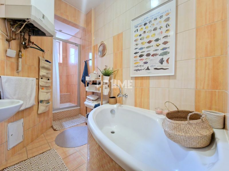 Koupelna v 3-pokojovém bytě s vanou, sprchovým koutem a košíky na doplňky.