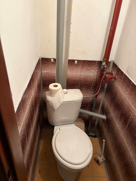 Toaleta s klasickým WC a rohovou dlažbou v chatě.