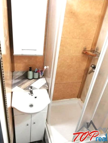 Koupelna s umyvadlem a sprchovým koutem v 1-pokojovém bytě.