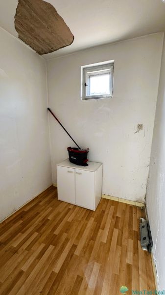 Malá místnost s oknem, skříní a podlahou s dřevěným dekorem v rodinném domě.