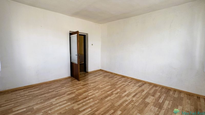 Pokoj v rodinném domě s podlahou s dřevěným dekorem a otevřenými dveřmi.