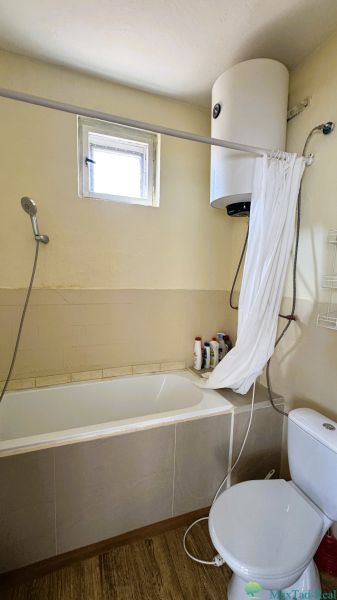 Koupelna s vanou, sprchou, bojlerem a podlahou s dřevěným dekorem v rodinném domě.
