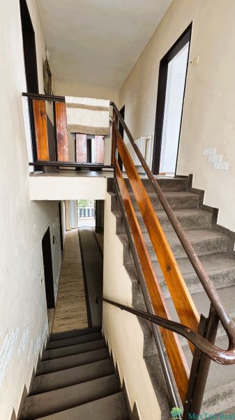 Schodiště v rodinném domě s dřevěným zábradlím a kobercem na schodech.