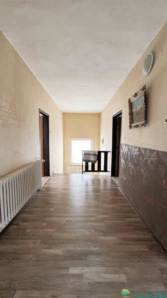 Chodba v rodinném domě s podlahou s dřevěným dekorem, ozdobnými stěnami a radiátorem.